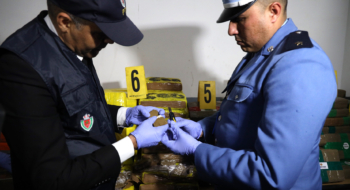 Un élément de la Sûreté nationale et un agent des douanes examinant la cargaison de chira saisie au port Tanger Med, le 19 mars 2026.