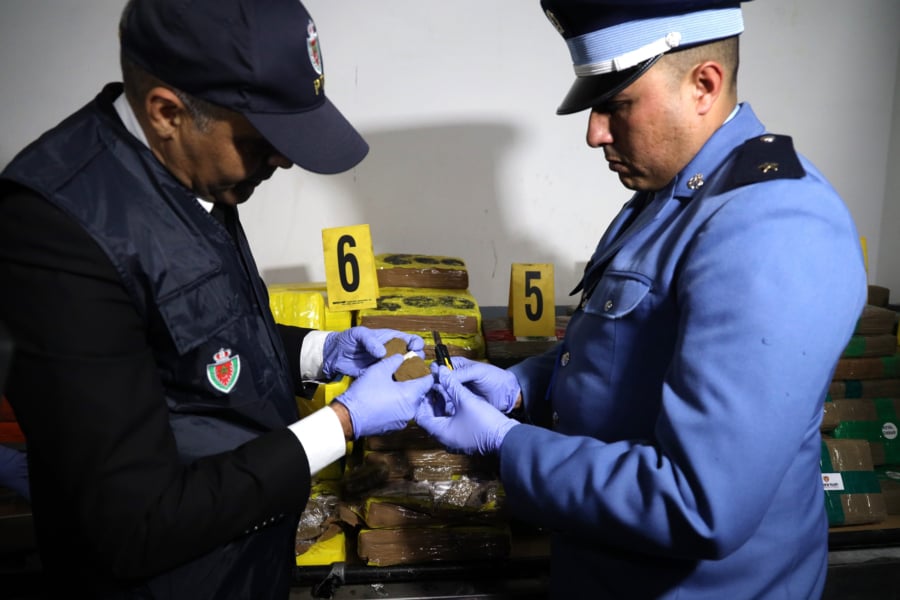 Un élément de la Sûreté nationale et un agent des douanes examinant la cargaison de chira saisie au port Tanger Med, le 19 mars 2026.