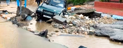 Une voiture bloquée dans les débris d'une chaussée endommagée par les inondations survenues à Safi, le 14 décembre 2025