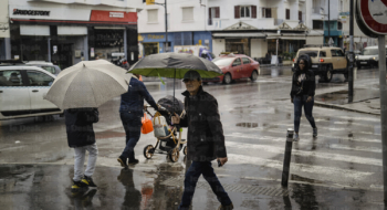 Des passant dans une artère de Casablanca sous la pluie.