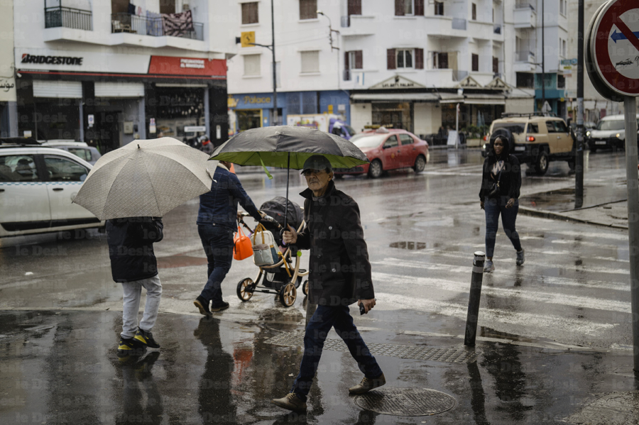 Des passant dans une artère de Casablanca sous la pluie.
