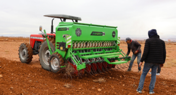 Des agricultures préparant un tracteur équipé d'un semoir mécanique sur une exploitation dans la région de l'Oriental.