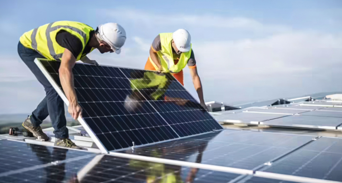 Des techniciens installant des panneaux solaires en toiture.