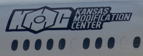 Un fuselage d'avion portant le logo de Kansas Modification Center (KMC), entreprise américaine spécialisée dans la conversion d'avions de passagers en avions cargo.