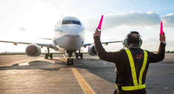 Un agent de piste de RAM Handling guidant un avion sur le tarmac.