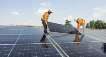 Des techniciens installant des panneaux solaires en toiture.
